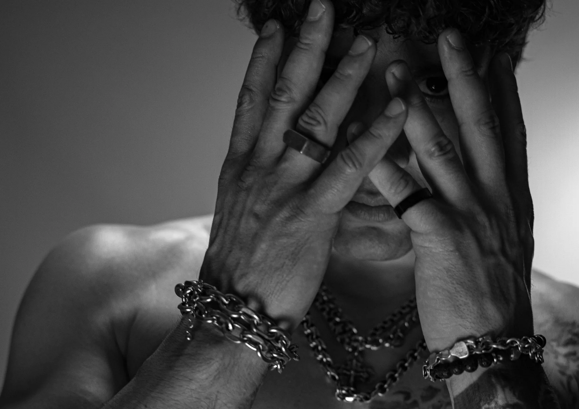 DISTEYO covering his face with both hands, chains around his wrists
